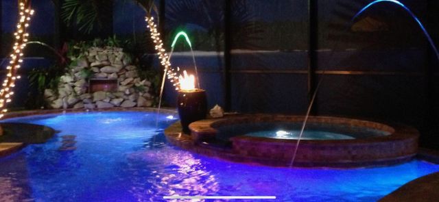 Fire feature burning beside an illuminated custom pool and spa